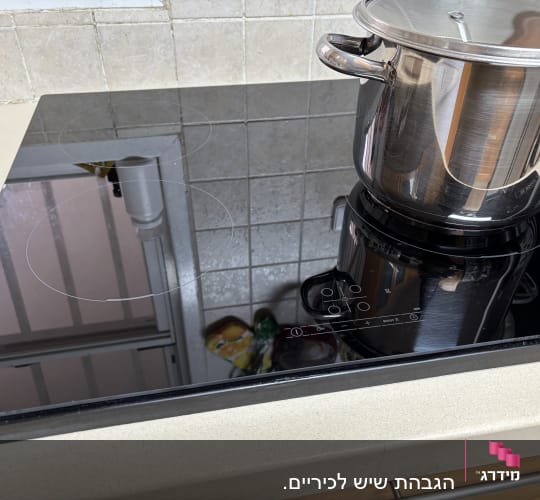 כיריים חשמליות עם סיר נירוסטה על משטח שיש